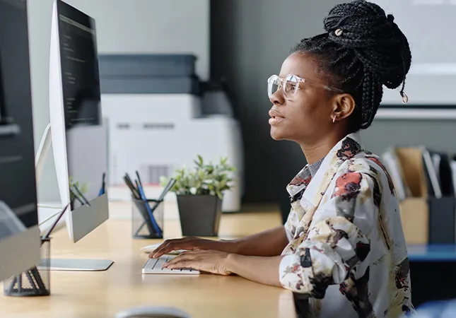 A woman using a mouse and looking at a computer screen.