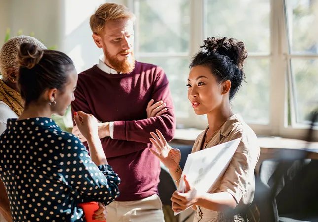 A group of people discuss something whilst standing together.