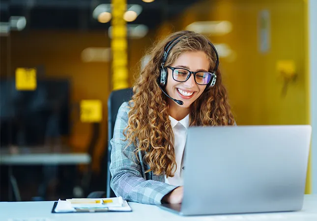 A women wearing a headset and using a laptop.