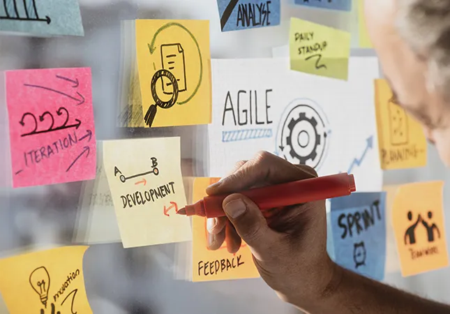 A person writing on post-it notes on a glass wall.