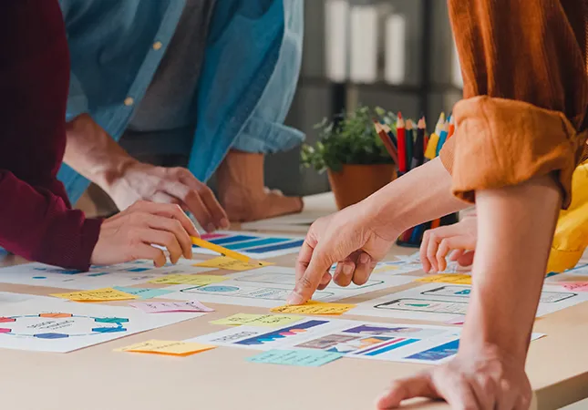 People standing at a table pointing at documents.