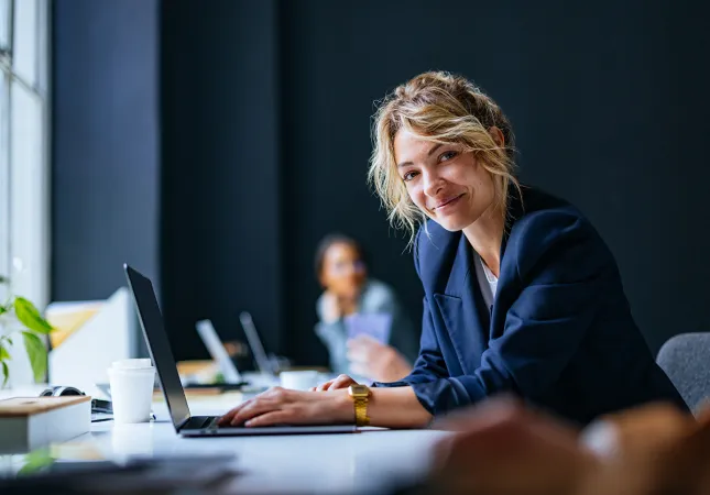 A woman using a laptop and smiling.