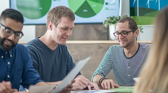 People sitting around a table reading documents related to sustainability.