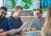 People sitting around a table reading documents related to sustainability.